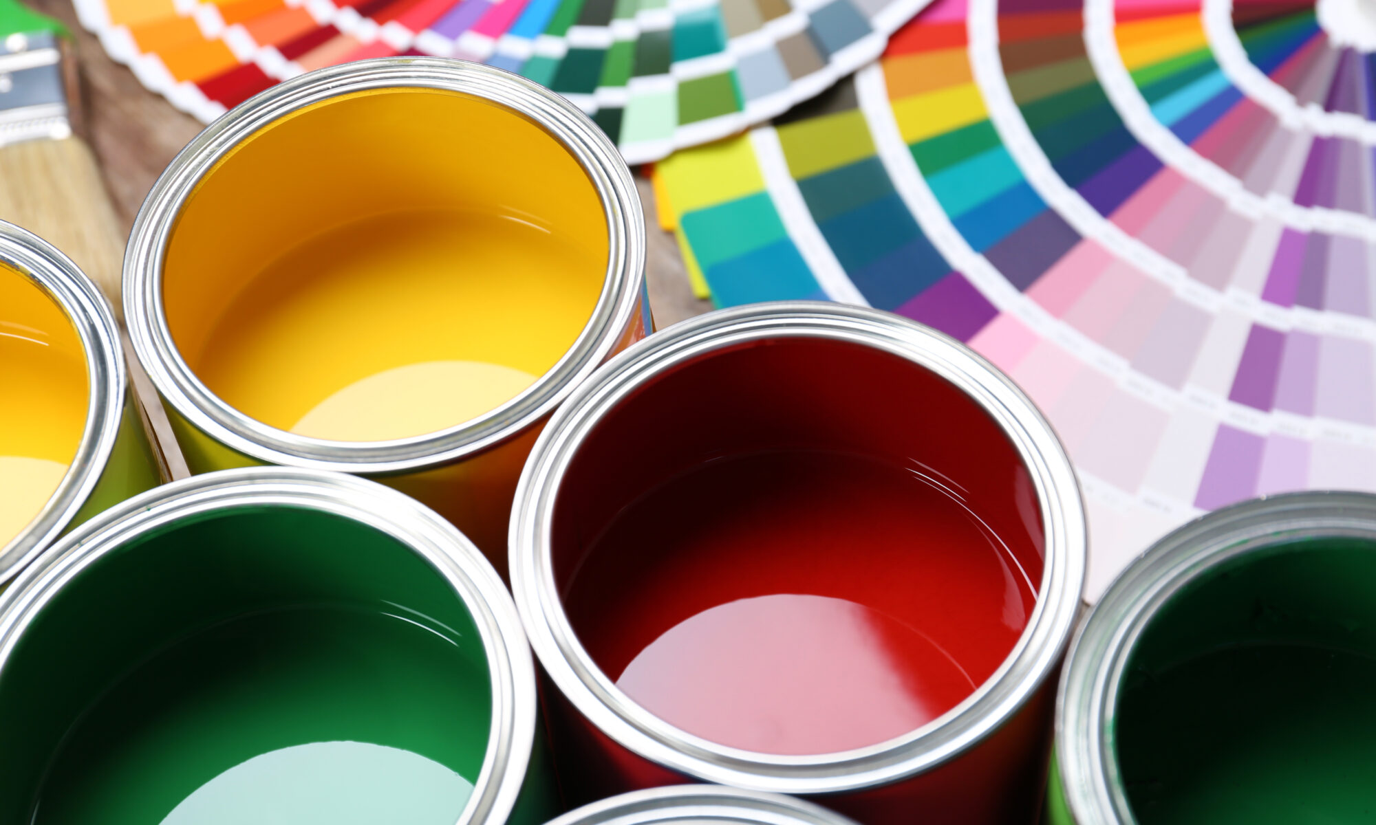 Multiple bright colors of paint in paint cans with color charts. Ingredient Handling and Mixing Solutions for the Paint & Coatings Industry - HaF Equipment Manufacturers.