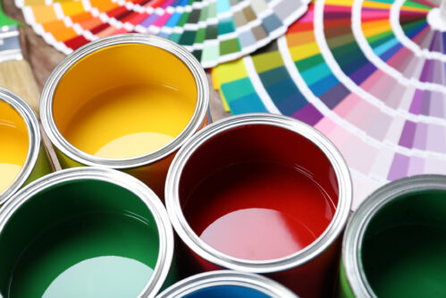 Multiple bright colors of paint in paint cans with color charts. Ingredient Handling and Mixing Solutions for the Paint & Coatings Industry - HaF Equipment Manufacturers.